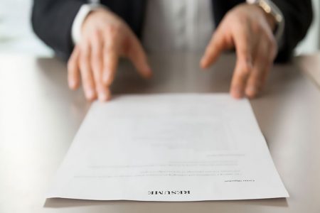 Resume document with guys hands in background. Recruitment manager reads resume. Job applicant offers CV to recruiter at interview. Employer examines achievements of new company worker. Close up photo